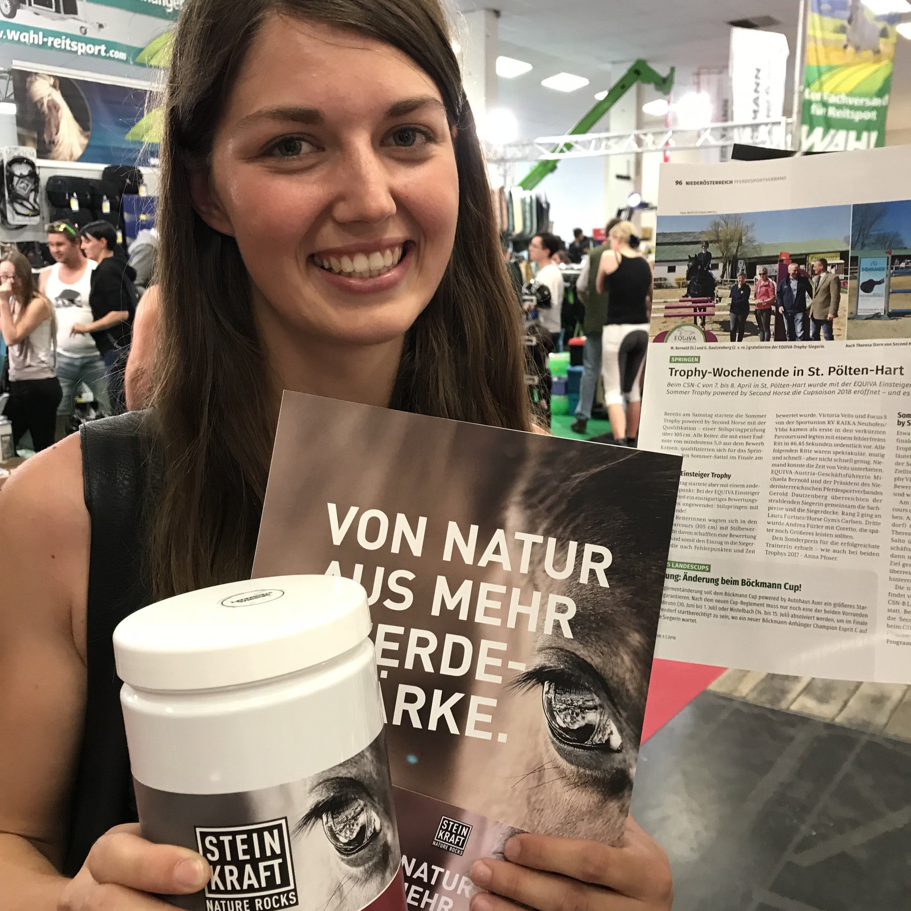 STEINKRAFT HORSEKRAFT Zeolith- Pellets 1,4kg - Kundin auf der Pferdemesse mit einer Dose Zeolith-Pellets und Steinkraft Folder in der Hand