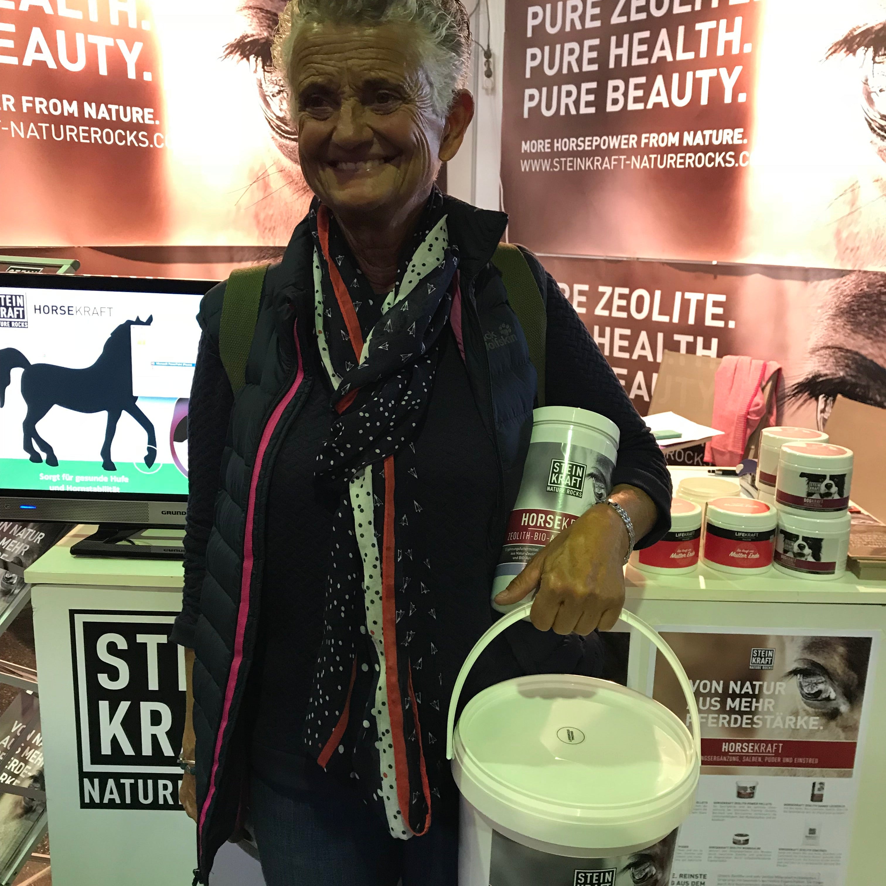 STEINKRAFT Zeolith für Pferde - Reitstallbesitzerin hat auf der APROPOS Pferd Messe Zeolith gekauft und hat 3kg Pulver und eine Dose Zeolith Pellets in der Hand.